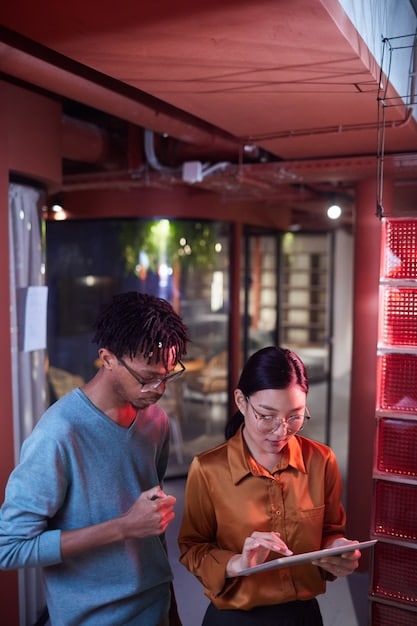 A store manager using a tablet to review sales data and communicate with staff via a digital dashboard. The background shows a busy retail environment with employees assisting customers.